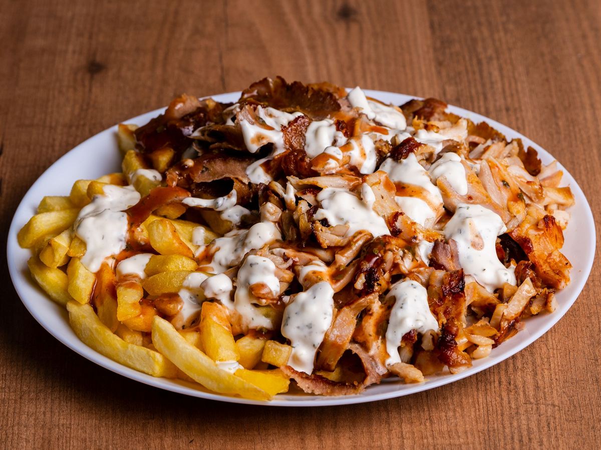Een bord friet met d&ouml;nervlees en knoflooksaus.